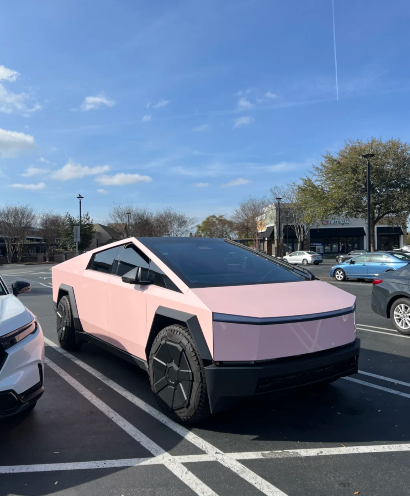 The rear view of a Tesla Cybertruck parked on a street, showcasing its unique angular design and metallic finish.