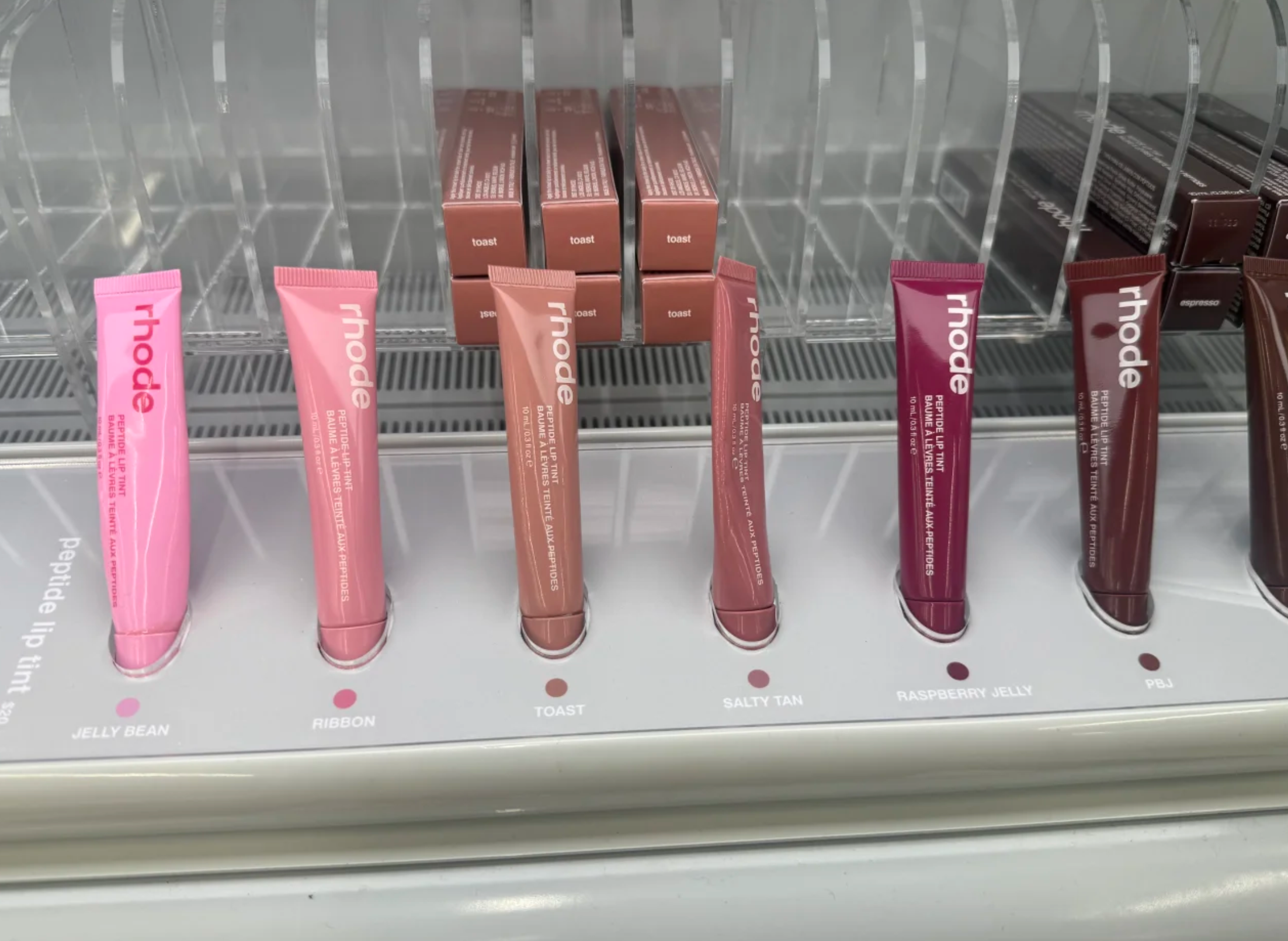 An eye-level view of a Sephora aisle with various beauty brands, emphasizing the prominence of Rhode in the current layout.