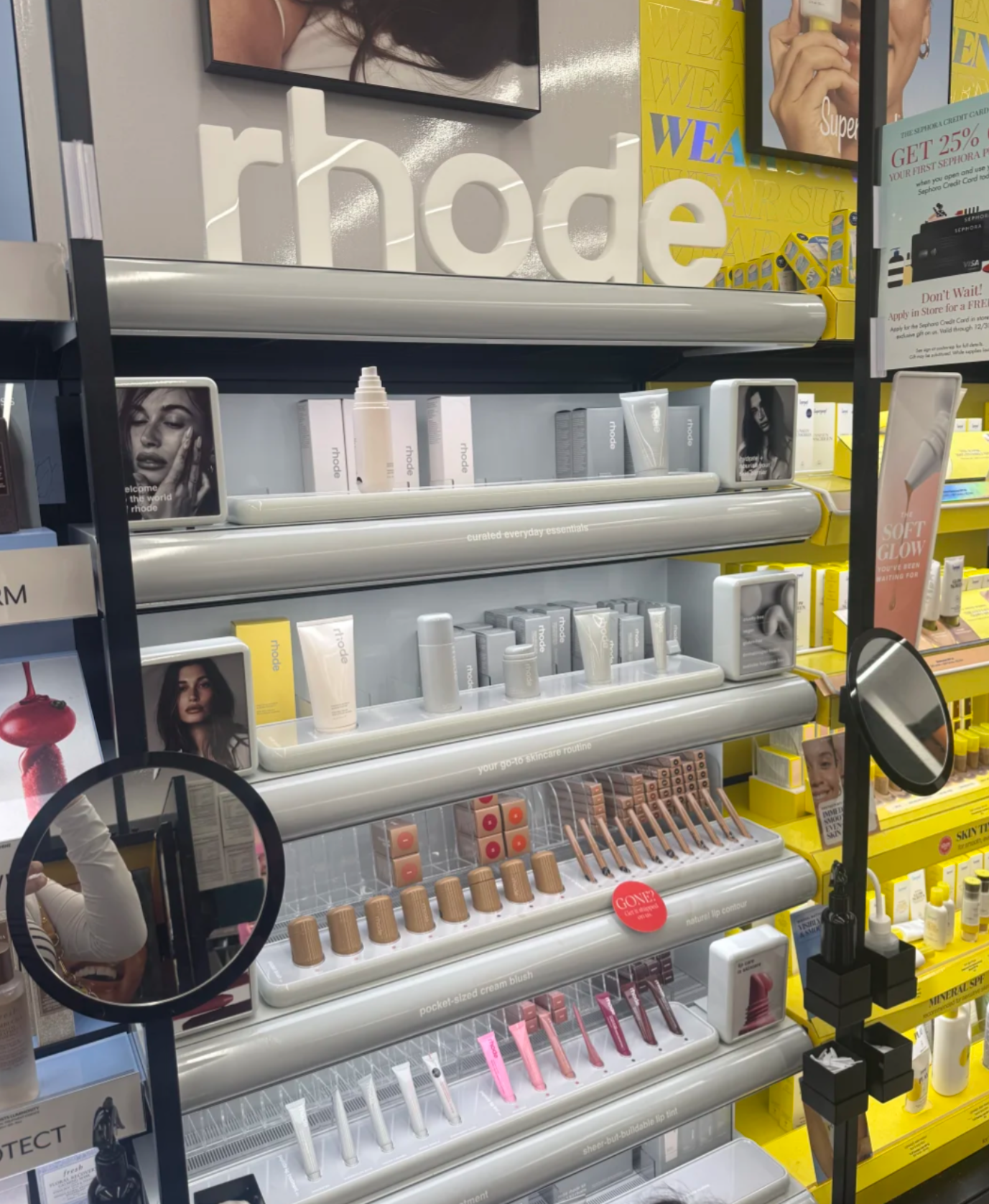 A hand holding a Rhode lip product, showcasing its sleek design.