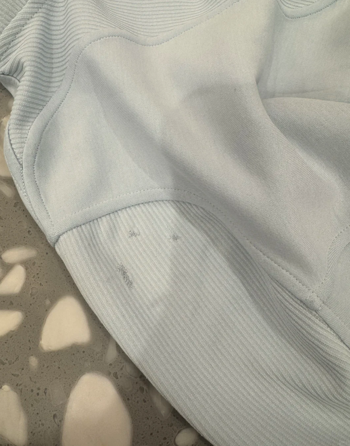 Close up of a badly repaired lululemon top with messy stitching and ruined fabric