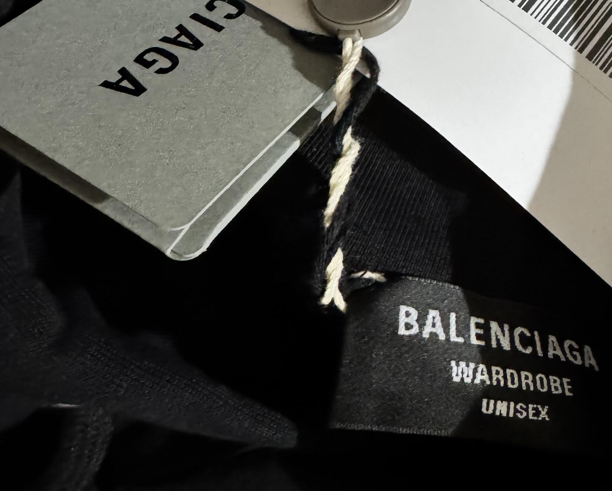 Close-up comparison of a fake designer wash tag with poor stitching and incorrect font next to an authentic tag, highlighting the quality difference.